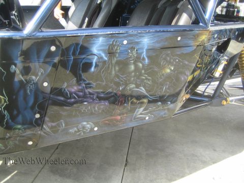 1990 Ford Bronco - Close-up of a body panel airbrushed with demons, skeletons and grim figures in blue and gray tones, mounted with visible fasteners on a cag…