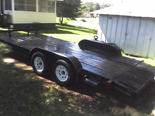 Black car trailer with dual axles and white rims