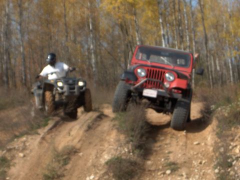 1979 Jeep CJ5 - Two off-road vehicles, a red Jeep CJ5 and an ATV, navigate a dirt trail during an event.
