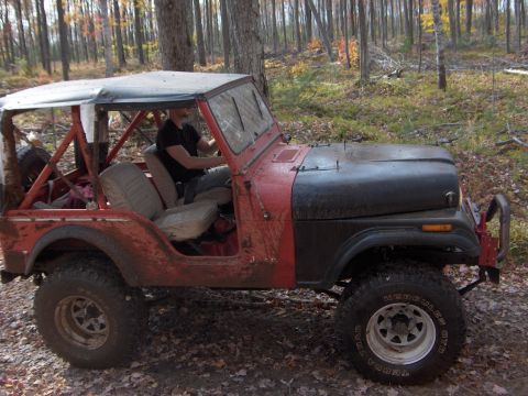 1979 Jeep CJ5 - This Jeep CJ-series is seen off-road in a forest with fallen leaves on the ground.
