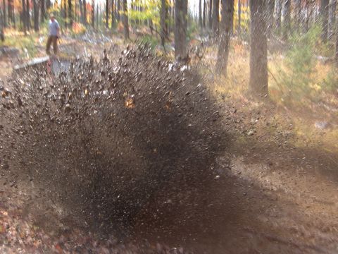 1979 Jeep CJ5 - A person stands in the background as a vehicle kicks up a large spray of mud.