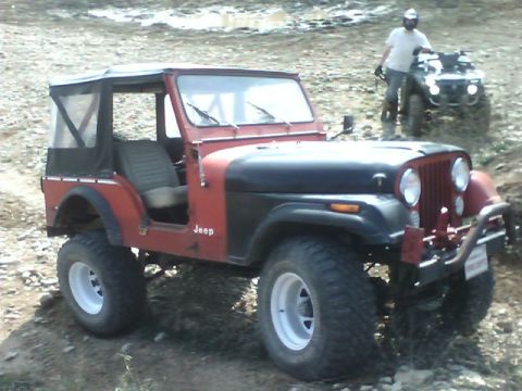 1979 Jeep CJ5 - A red and black Jeep CJ5 is parked on a dirt path with an ATV in the background.