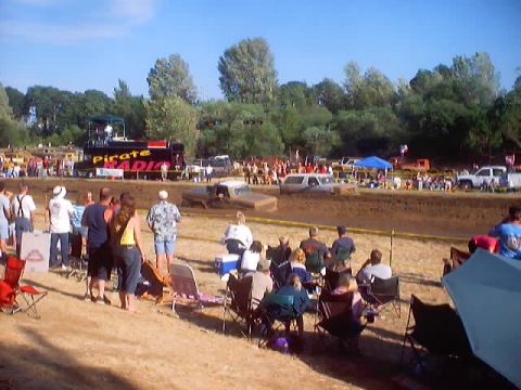 1976 Ford F-100 - Spectators watch trucks compete in a mud bog event on a sunny day.