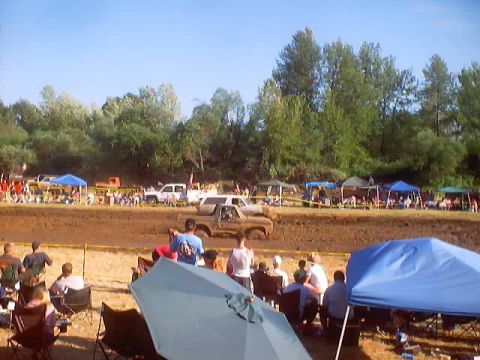 1976 Ford F-100 - Spectators watch as a truck navigates a muddy track during an event.