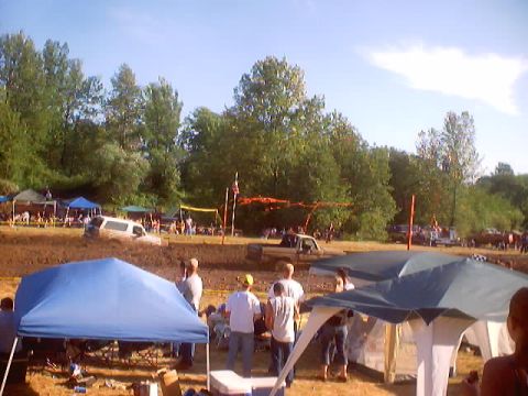 1976 Ford F-100 - A truck is stuck in a mud pit during an event, with spectators gathered around.
