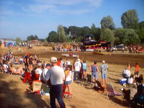 1976 Ford F-100 - Spectators watch a mud bog event with a truck stuck in the mud and a trailer labeled 'PIRATE'.