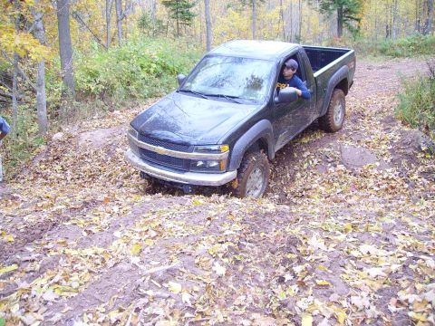2000 Chevrolet Tahoe - Pickup truck stuck in mud on a wooded trail during autumn.