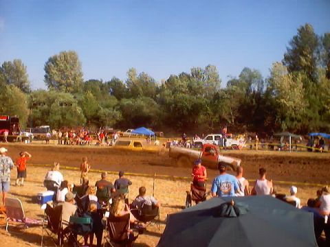 1976 Ford F-100 - Spectators watch trucks compete in a mud bogging event on a sunny day.
