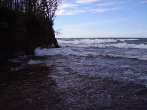 2000 Chevrolet Tahoe - Waves crash against a rocky cliff on a cloudy day.