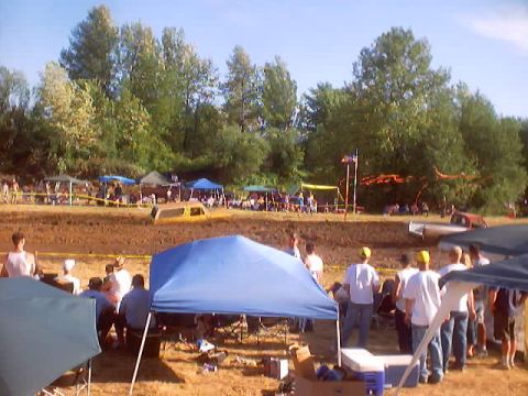 1976 Ford F-100 - A yellow pickup truck is stuck in the mud at an outdoor event with spectators and tents.