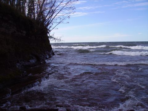 2000 Chevrolet Tahoe - A rocky shoreline meets choppy water under a partly cloudy sky, with trees on the left bank.
