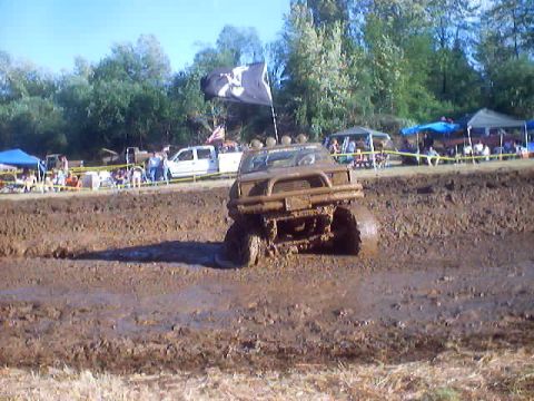 1976 Ford F-100 - Mud bogging event with a truck stuck in the mire and spectators watching.