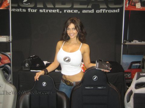 1990 Ford Bronco - woman in a white tank top stands behind two black Corbeau racing seats at a seats-for-street-race-and-offroad booth.