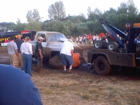 1976 Ford F-100 - A muddy 1973 Ford F-150 pickup truck is being towed out of a mud pit at an event.