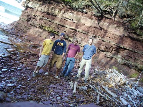 2000 Chevrolet Tahoe - A group of friends pose for a photo on a beach with a large rock formation behind them.