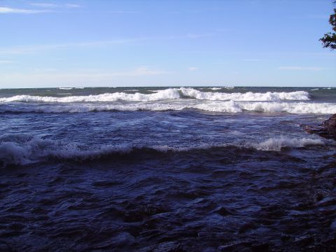 2000 Chevrolet Tahoe - Waves roll onto a rocky shoreline under a clear blue sky.