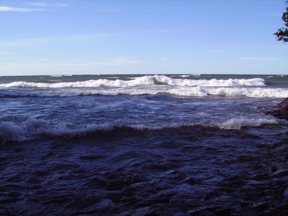 Ocean waves crash on a rocky shore under a blue sky