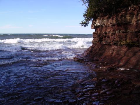 2000 Chevrolet Tahoe - Waves crash against a rocky shoreline under a clear blue sky. The image includes a watermark for SUPERMOTORS.