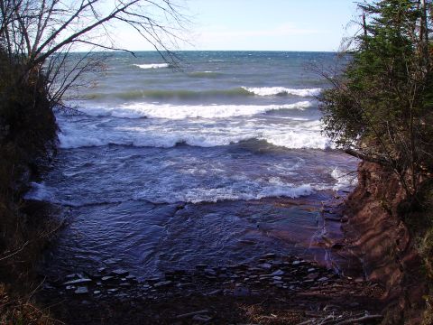 2000 Chevrolet Tahoe - Waves break against a rocky shore under a clear sky.