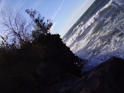 2000 Chevrolet Tahoe - Waves crash against a rocky shore under a bright blue sky.
