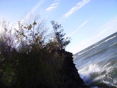 2000 Chevrolet Tahoe - Waves crash against a rocky shore on a bright, sunny day with scattered clouds.
