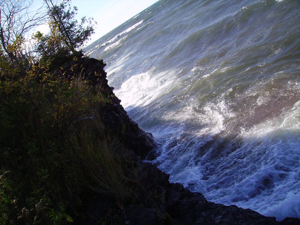 Stormy water crashing on rocky shore with trees