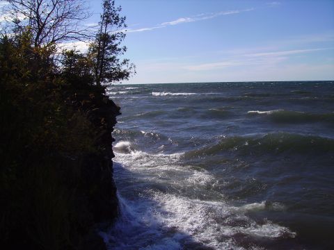 2000 Chevrolet Tahoe - Waves surge against a rocky coastline on a bright, clear day.