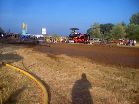 1976 Ford F-100 - A muddy field with spectators gathered around a 'Pirate Radio' booth and vehicles.