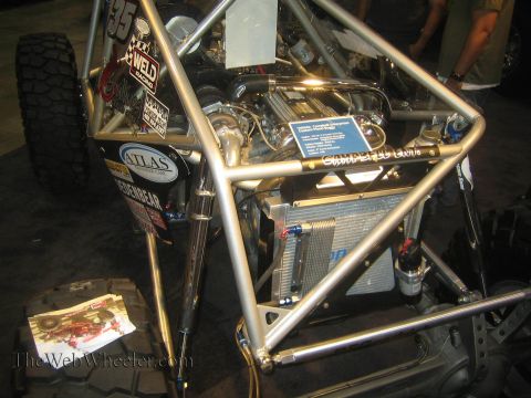 1990 Ford Bronco - Rear view of a polished tube-chassis buggy showing its engine, oil cooler, fuel tank and inboard coilover shocks at a show.