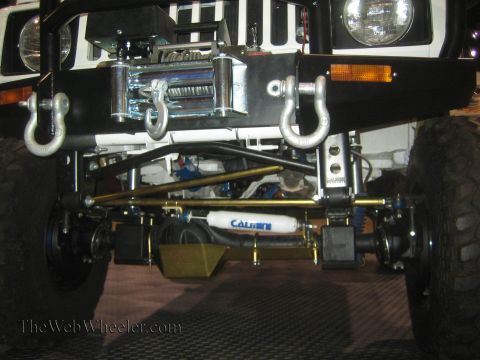 1990 Ford Bronco - Front underbody view of a white 4x4 showing the winch, tie rod steering, gold skid plate and a Calmini-labeled component.