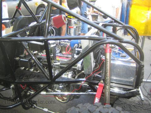 1990 Ford Bronco - Close detail of a black tube-chassis buggy showing the engine, red cone air filter, fuel cell, and a red coilover shock.