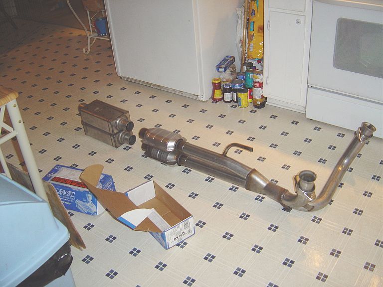 Stainless exhaust system parts laid out on a kitchen floor