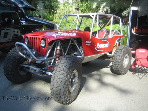 1990 Ford Bronco - red tube-frame Jeep-style rock crawler with a full roll cage, Rancho shocks and oversized off-road tires sits at an outdoor display.
