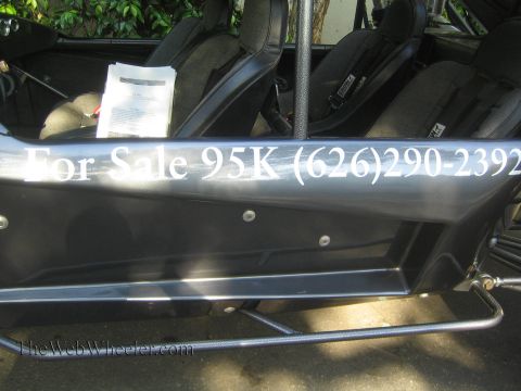 1990 Ford Bronco - Close-up of a black off-road buggy's side body panel reading For Sale 95K with a phone number, showing bucket seats and harnesses inside.