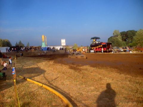 1976 Ford F-100 - A 1976 Ford F-100 navigates a muddy track during an event, with spectators and a 'Pirate Radio' truck in the background.