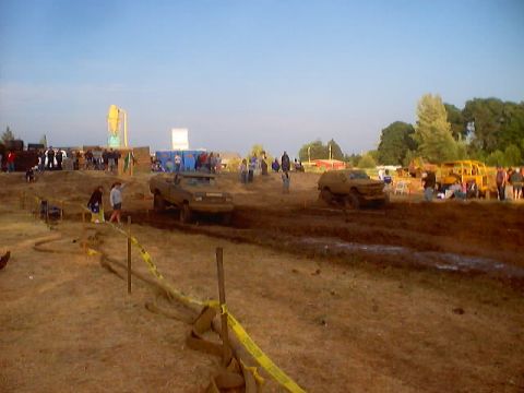 1976 Ford F-100 - Trucks navigate a muddy course during a mud bogging event with spectators present.