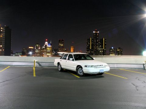 2003 Ford Crown Victoria - White 2003 Ford Crown Victoria parked on a rooftop with a city skyline at night.