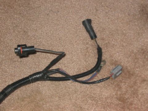 1991 Ford Bronco - A close-up view of an automotive wiring harness with various connectors and protective tubing.