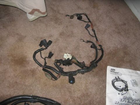 1991 Ford Bronco - A Ford Motorsport engine wiring harness and installation manual are laid out on a carpeted floor.