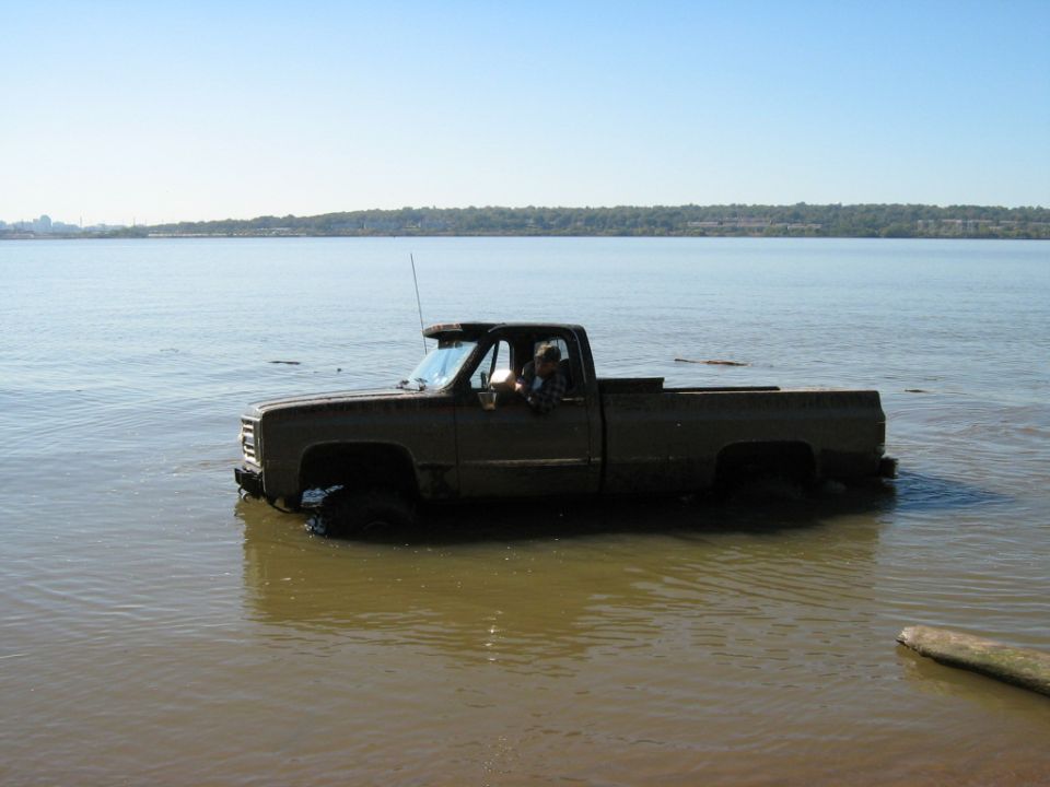 Brown pickup truck driving through shallow water