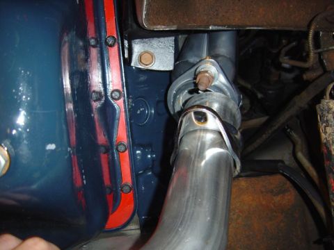 1986 Ford Bronco - Close-up underhood/undercarriage view of a polished stainless steel exhaust pipe connected to a component with a threaded stud and clamp, m…