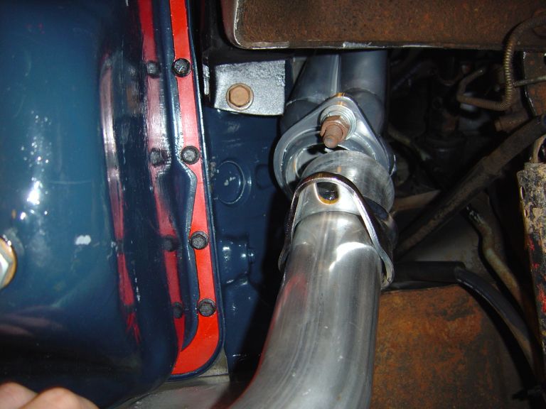 Polished stainless exhaust pipe joined with clamp near blue engine panel
