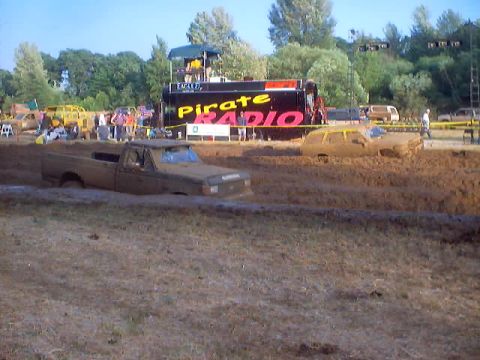1976 Ford F-100 - Mud bog event features a 1976 Ford F-100 struggling in the mire, with a "Pirate Radio" truck nearby.