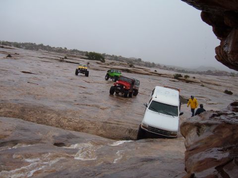 1993 Ford Bronco - Multiple off-road vehicles traverse a slick, rocky landscape under overcast skies.