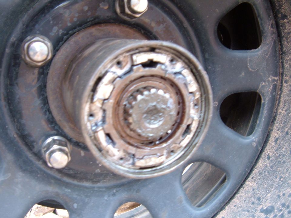 Close-up of damaged front locking hub internals with splined axle stub inside black steel wheel