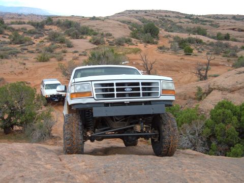 1993 Ford Bronco - A white Ford Bronco navigates a rocky trail, with another vehicle following behind.