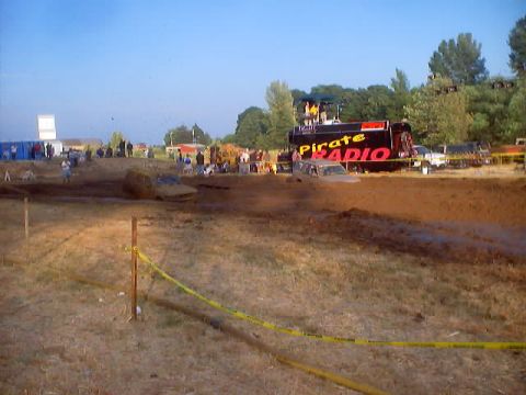 1976 Ford F-100 - Vehicles are stuck in the mud at an event, with a large truck labeled 'Pirate Radio' in the background.