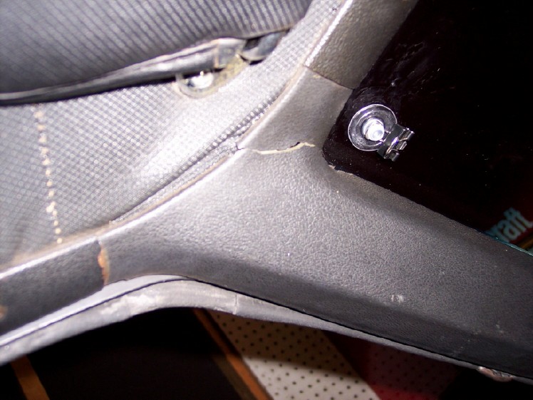 Closeup of gray seat trim panel and chrome mounting bolt on a workbench