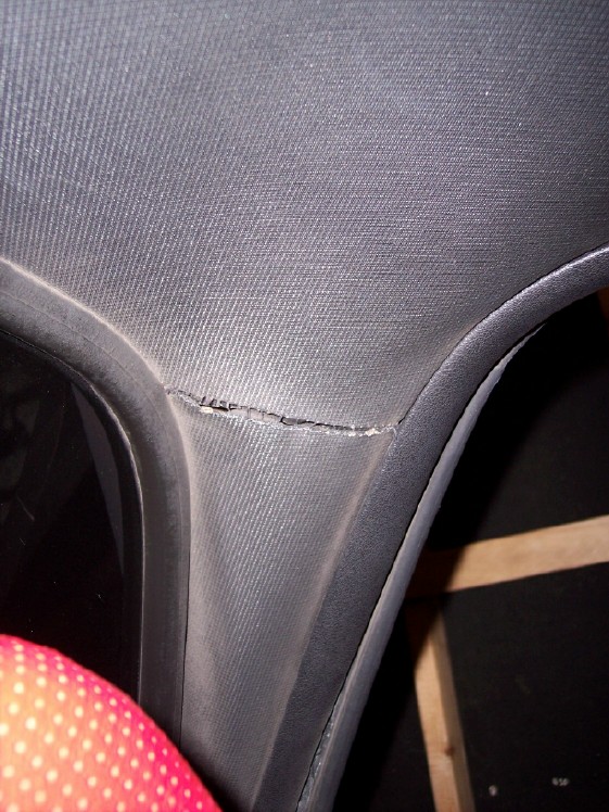 Torn seam in gray cloth interior trim panel beside black weatherstrip