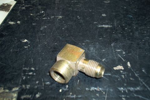 1983 Ford Bronco - A close-up view of a brass-colored metal fitting with threaded connections.